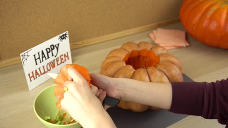 Women's-hands-clean-the-pumpkin-cover-from-the-seeds-for-halloween