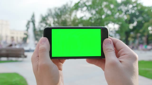 Manos-sosteniendo-un-teléfono-con-una-pantalla-verde