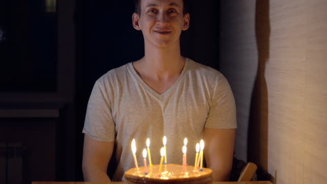 Young-man-blows-out-candles-on-a-festive-cake