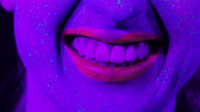 Closeup-labios-de-mujer-con-maquillaje-fluorescente,-maquillaje-creativo-lucen-muy-bien-para-discotecas.-Concepto-de-fiesta,-espectáculos-y-música-de-Halloween---slow-motion-video