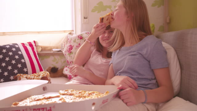 Mädchen-lachen-und-füttern-Ihrem-Freund-pizza-im-Bett