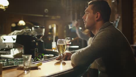 Lapso-de-tiempo-vídeos-de-un-hombre-sentado-sola-con-una-cerveza-en-el-bar-mientras-las-personas-se-encuentran-con-un-buen-momento.