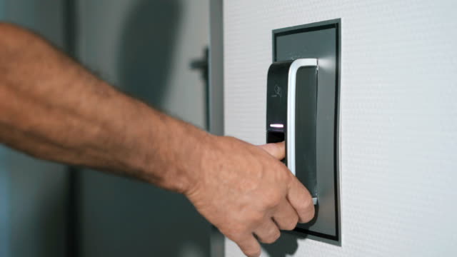 The-man-puts-his-finger-on-a-fingerprint-scanner-which-is-designed-to-enter-the-door.-Modern-security-technology-in-everyday-lives-of-employees.-Work-of-protection-against-burglary-close-up