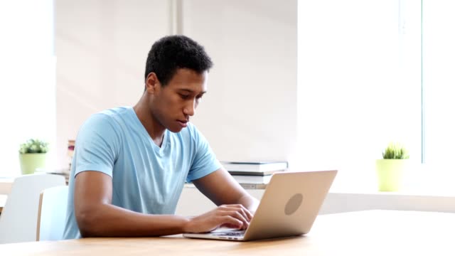 Junge-schwarze-Mann-arbeitet-auf-Laptop