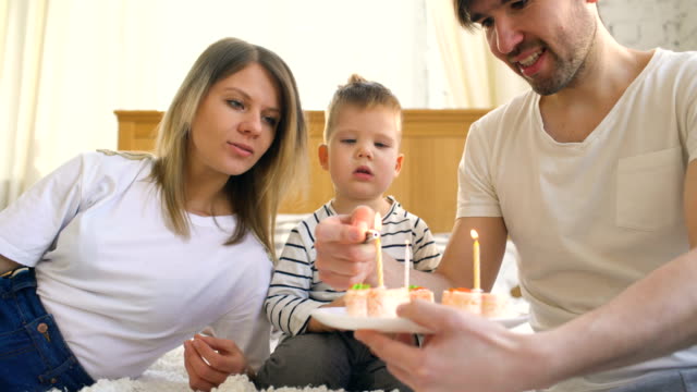Smiling-family-celebrating-their-son-birthday-together-before-blowing-candles-on-cake