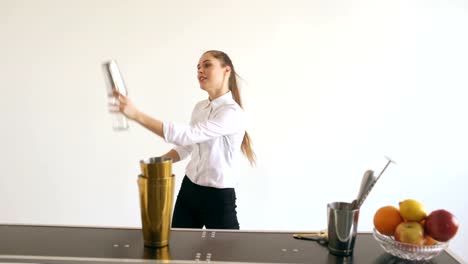 Professinal-Barkeeper-Mädchen-Jonglieren-Flaschen-und-schütteln-Cocktail-am-mobilen-Bar-Tisch-auf-weißem-Hintergrund-Studio-drinnen