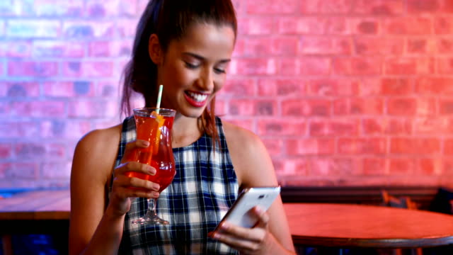 Happy-woman-taking-selfie-on-mobile-phone-while-having-cocktail