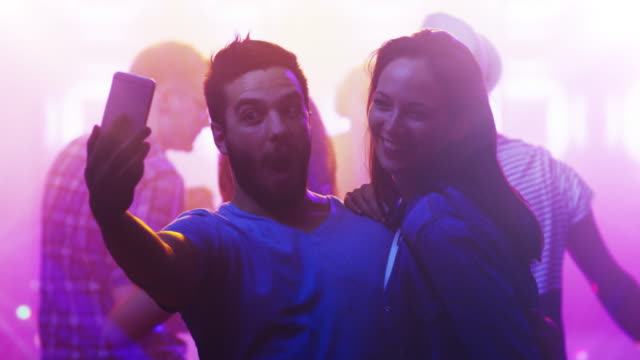 Junger-Mann-und-Frau-tanzen-zusammen,-dabei-Selfie-im-Nachtclub.