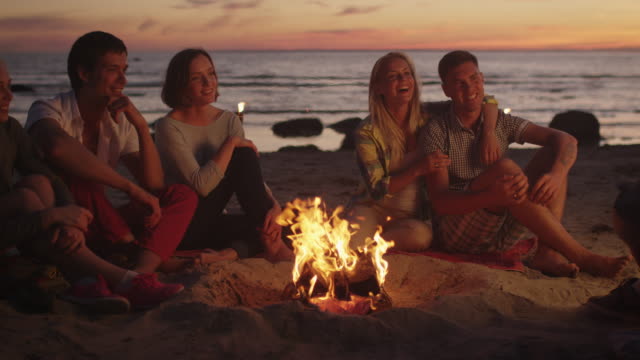 Group-of-Friends-Sitting-near-Campfire-at-Night-and-Hanging-Out