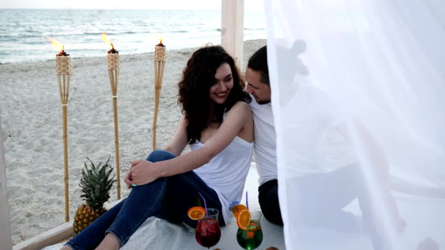 Brautpaar-mit-Cocktails,-haben-Spaß,-Bungalow-mit-weißen-Tuch,-einen-exotischen-Urlaub-auf-Hintergrund-tropische-Früchte,-brennenden-Fackeln