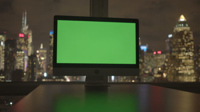 Ordenador-con-pantalla-verde-en-moderno-edificio-de-oficinas-con-fondo-de-paisaje-urbano.