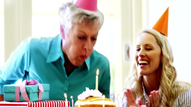 Ältere-Frau-Ausblasen-der-Kerzen-auf-einem-Geburtstagskuchen