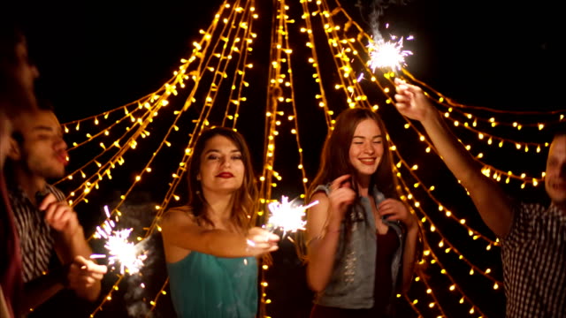 Happy-friends-dancing-with-sparklers-at-night-party