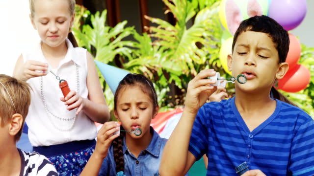 Happy-friends-playing-with-bubble-wand-in-backyard-4k