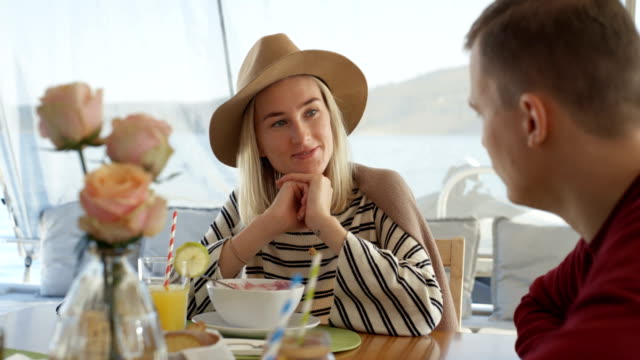 Young-Couple-Talking-While-Having-Breakfast-on-the-Yacht.-Beautiful-People-with-Seascape-in-the-Background.