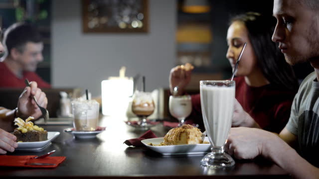 junge-Menschen-sind-köstliche-Desserts-und-trinken-Kaffee-und-Cocktails-in-einem-Restaurant-Abend-essen