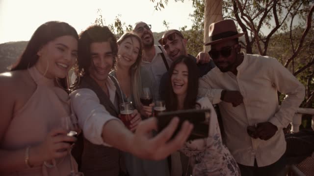 Multi-ethnic-friends-celebrating-and-taking-selfies-at-traditional-mountain-house