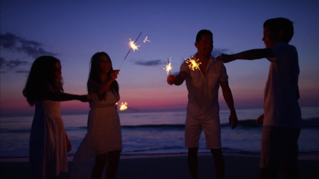 Sunset-silhouette-of-Hispanic-family-partying-with-sparklers