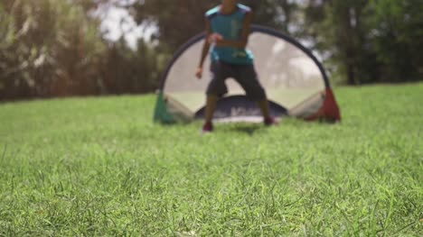 Niños-felices-en-el-campamento-de-verano-jugando-fútbol-coinciden-en-los-niños-de-campo-de-pasto-verde-patadas-pena-portero-lenta