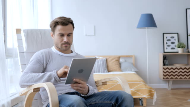 Hombre-usando-la-Tablet-mientras-está-sentado-en-la-silla