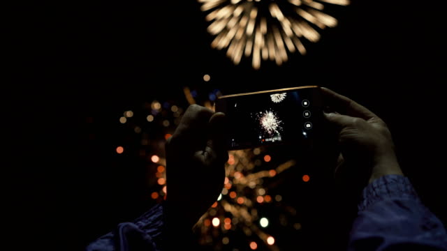 Silhouette-of-a-man-photographing-fireworks-at-night-sky.-Beautiful-salute-in-honor-of-the-holiday