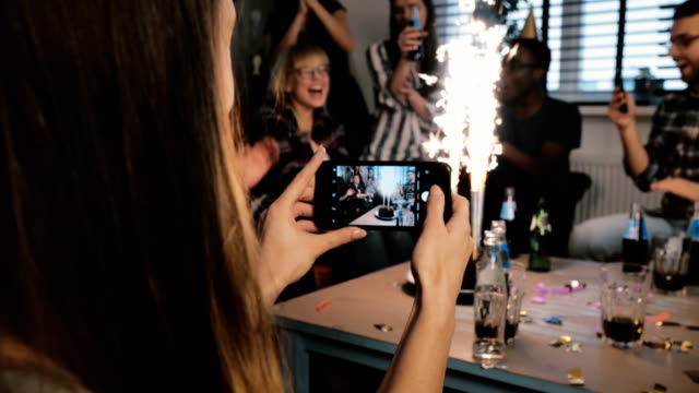 Mädchen,-die-ein-Smartphone-Foto-Geburtstagsfeier-mit-funkelnden-Feuerwerk-und-multiethnischen-Freunde-klatschten-Zeitlupe