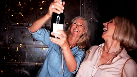 Mujeres-maduras-felices-celebrando-con-champán-y-confeti-en-la-noche