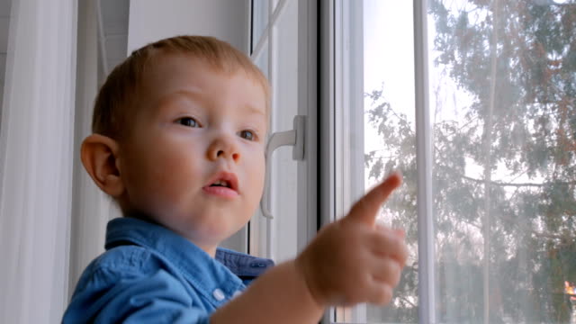 Pensive-little-boy-looking-through-window