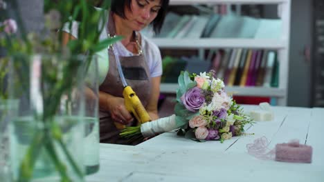 professionellen-Floristen-arrangieren-mit-Band-Hochzeit-Blumenstrauß-im-floralen-Designstudio