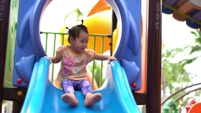 Asiatisches-Babymädchen-spielen-Schieberegler-am-Spielplatz.