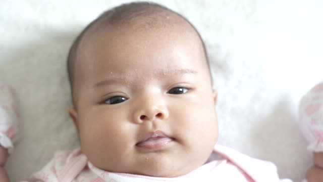 Un-bebé-recién-nacido-asiático-se-acueste-sobre-la-cama-blanca.