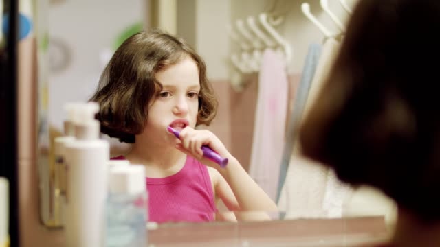 Kleines-Mädchen-putzen-ihre-Zähne-vor-dem-Spiegel