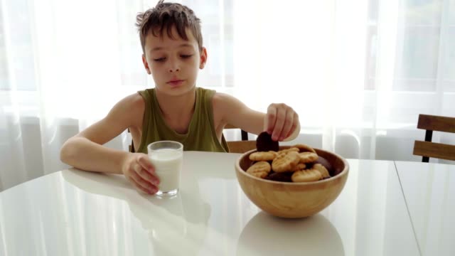 niño-comer-galletas-hechas-en-casa-con-leche-en-la-cocina-casera.