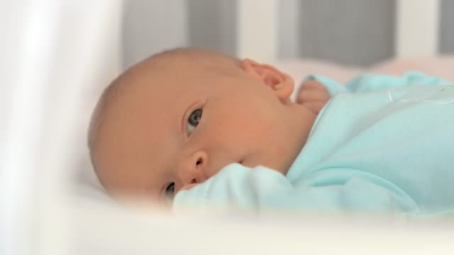 Newborn-baby-lying-quietly-in-bed