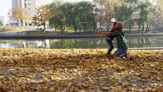 Joven-madre-divirtiéndose-con-su-hijo-en-el-Parque-otoño-en-día-soleado