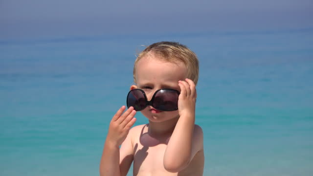 Lustige-junge-versuchen,-Sonnenbrille,-verärgert-zu-scheitern,-wunderschönen-türkisfarbenen-Meer-zu-arrangieren