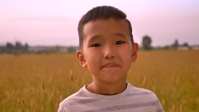 Young-happy-asian-kid-enjoying-sunset-on-wheat-field