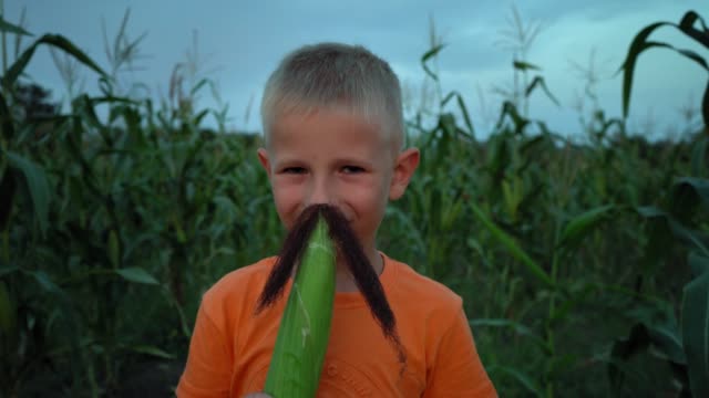 A-boy-with-corn-silk-mustache.-Boy-making-a-mustache-from-corn-hair