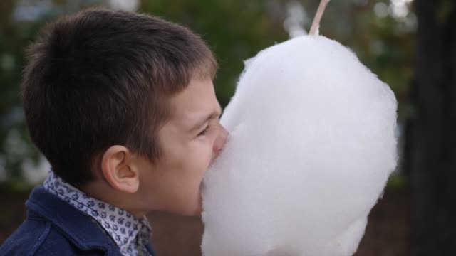 Happy-caucasian-Teen-boy-eating-cotton-candy.-Childhood-dreams-and-memories.-4k.-Slow-motion