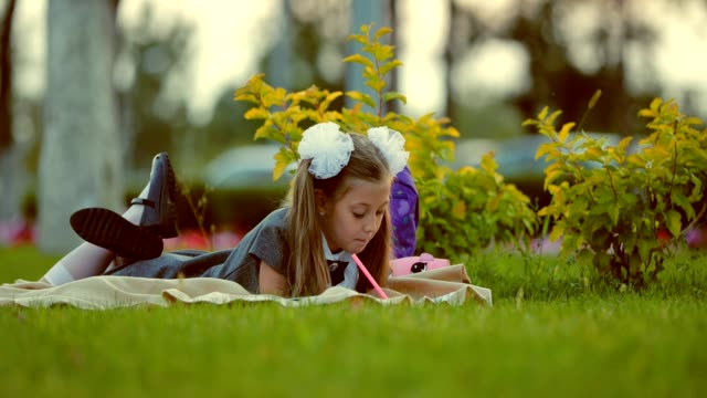 Junges-Mädchen-im-Freien-auf-dem-Rasen-liegen-und-Zeichnung
