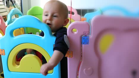 Baby-Boy-Standing-In-Colorful-Playpen