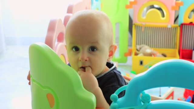Baby-Boy-Standing-In-Colorful-Playpen