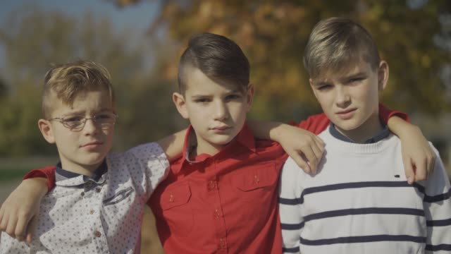 Three-young-boys-embracing-in-the-park.-Little-brothers-spending-time-together-outdoors.