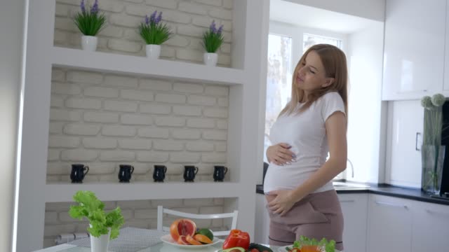 alimentos-vitaminas-para-el-embarazo,-encantadora-futura-madre-con-gran-Panza-bailando-en-la-cocina-en-vez-de-brunch-con-verduras-frescas-y-frutas-en-Apartamento