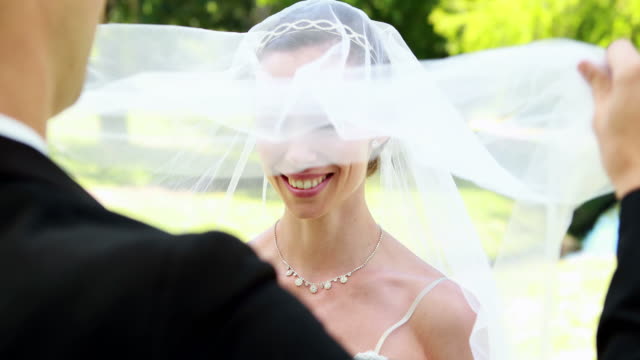 Groom-lifting-veil-off-beaming-brides-face