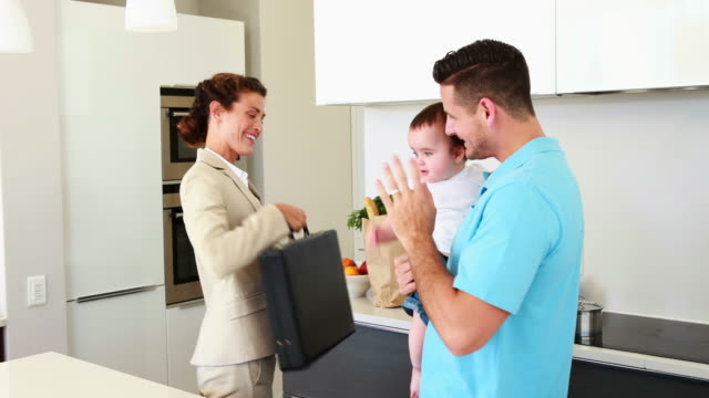 Working-mother-waving-goodbye-to-house-husband-and-baby