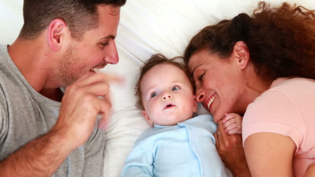 Baby-boy-in-blue-babygro-with-happy-parents-on-bed