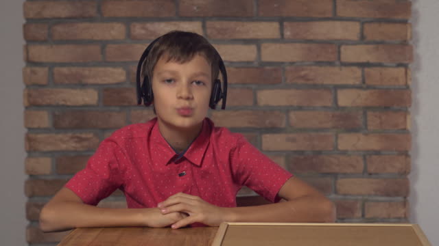 Kind-sitzt-am-Schreibtisch-mit-Flipchart-mit-Schriftgeräuschen-auf-der-roten-Backsteinwand