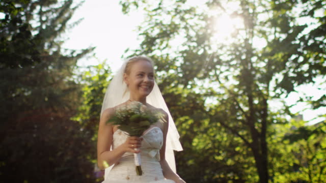Feliz-joven-novia-está-corriendo-en-un-bosque-soleado-en-vestido-de-novia.