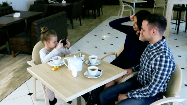 Moderne-Mädchen-macht-Fotos-von-schönen-Eltern-im-café